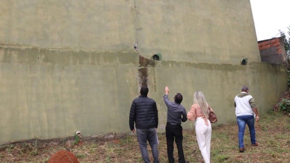 Pessoas em terreno vazio com parede rachada na Câmara de Itupeva