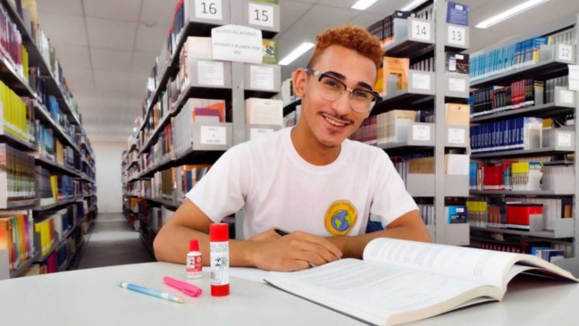 Jovem sentado em biblioteca