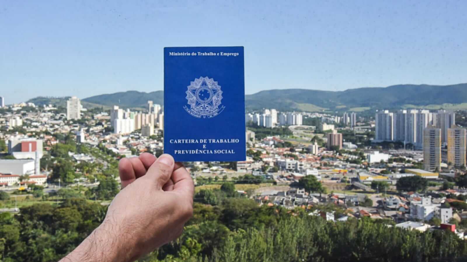 Carteira de trabalho com cidade ao fundo