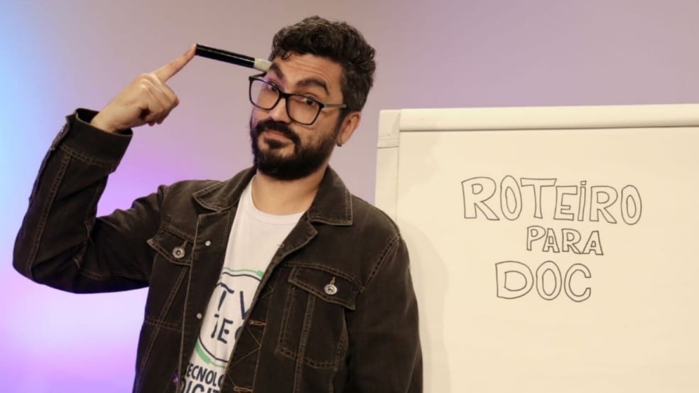 Homem em frente a quadro branco, escrito 'roteiro para doc'