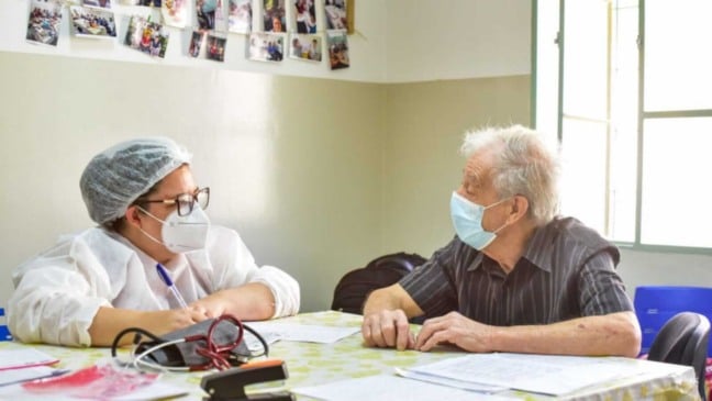 Mulher atendendo idoso em UBS