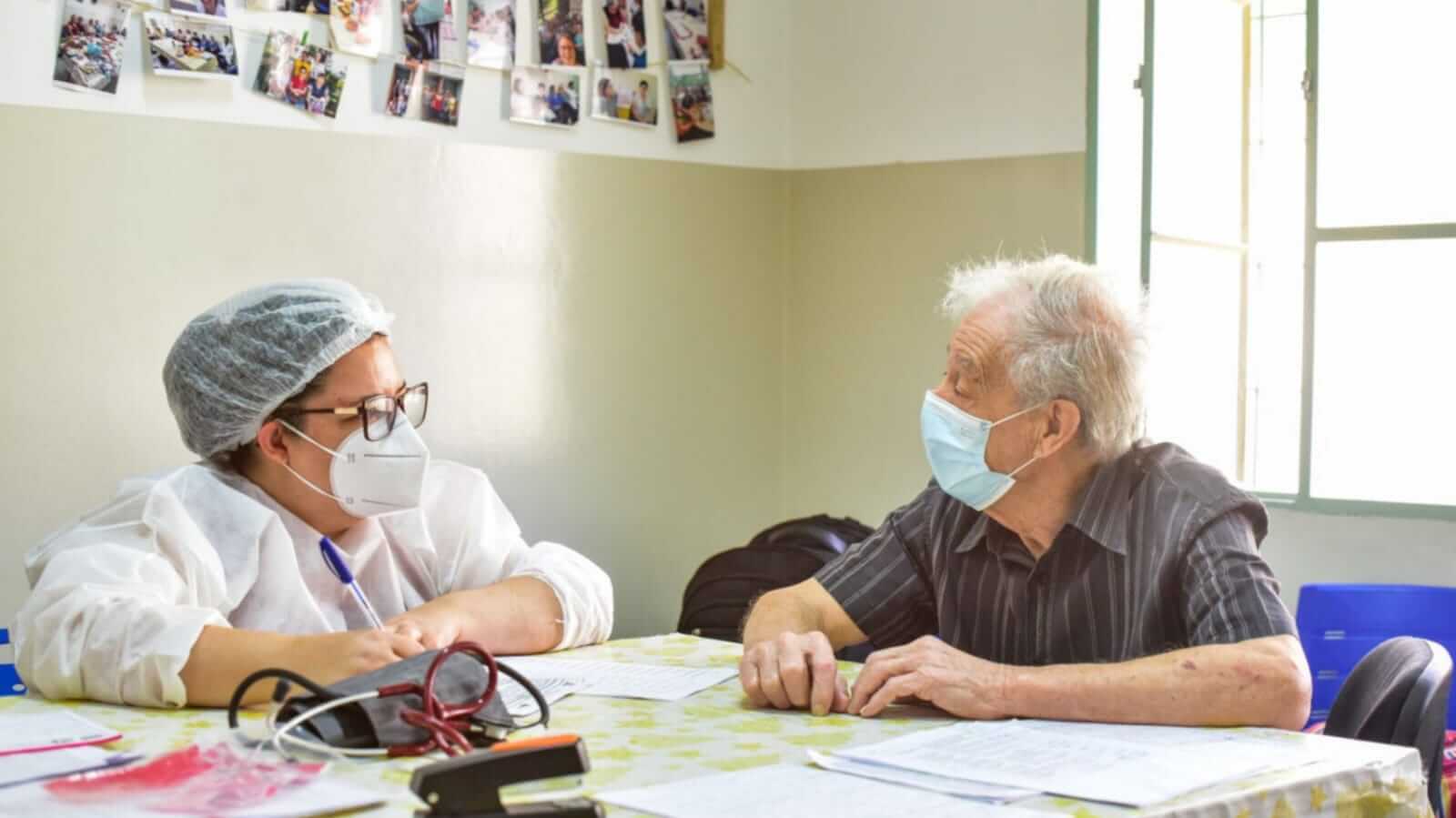 Mulher atendendo idoso em UBS