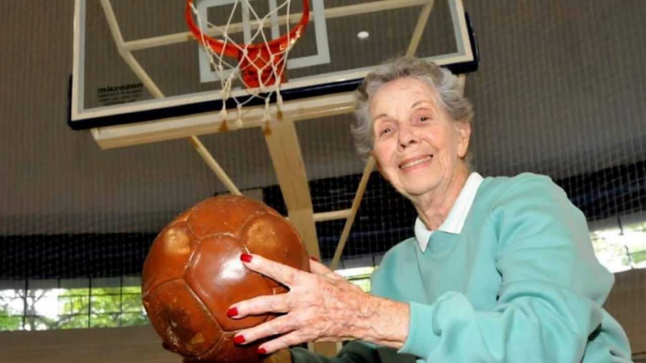 Idosa com bola de basquete em frente à cesta
