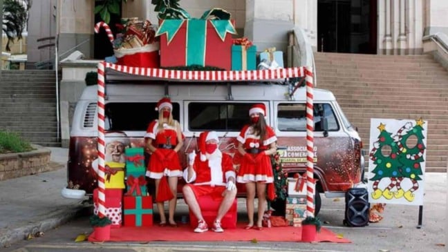 Kombi de Natal da ACE Jundiaí, com papai noel e noeletes em frente à igreja