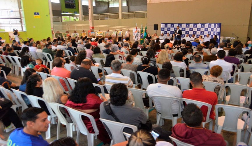 várias cadeiras plásticas em espaço amplo dentro do parque da uva de jundiaí, onde as pessoas estão sentadas acompanhando a formatura das turmas do fundo social de solidariedade