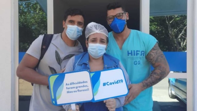 Dois homens abraçando a mãe do lado de fora de hospital.