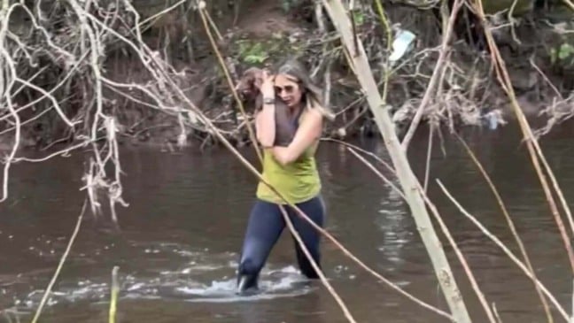 Mulher em rio com cachorro no colo