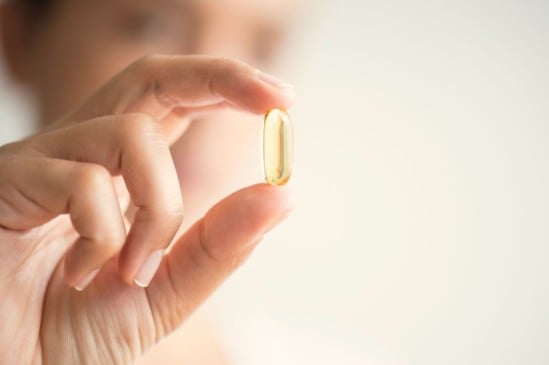 Mulher segurando cápsula de ômega 3