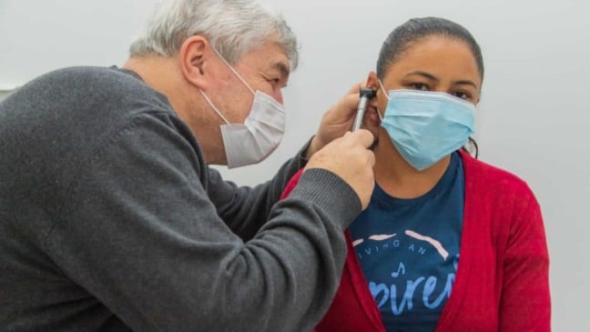 Médico consultando ouvido de mulher