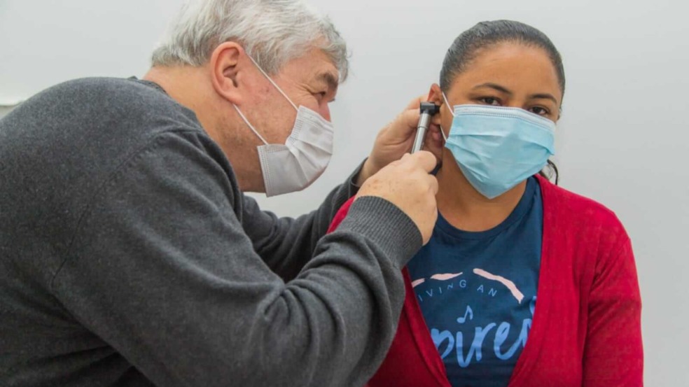 Médico consultando ouvido de mulher