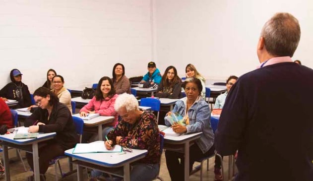 sala de aula com alunos da Educação de Jovens e Adultos, com professor de costa à frente e os alunos sentados ao fundo