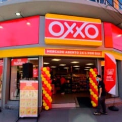 Fachada da loja OXXO em Jundiaí com letreiro vermelho e amarelo, entrada decorada e pessoas passando em frente. Fachada da loja OXXO em Jundiaí com letreiro vermelho e amarelo, entrada decorada e pessoas passando em frente.