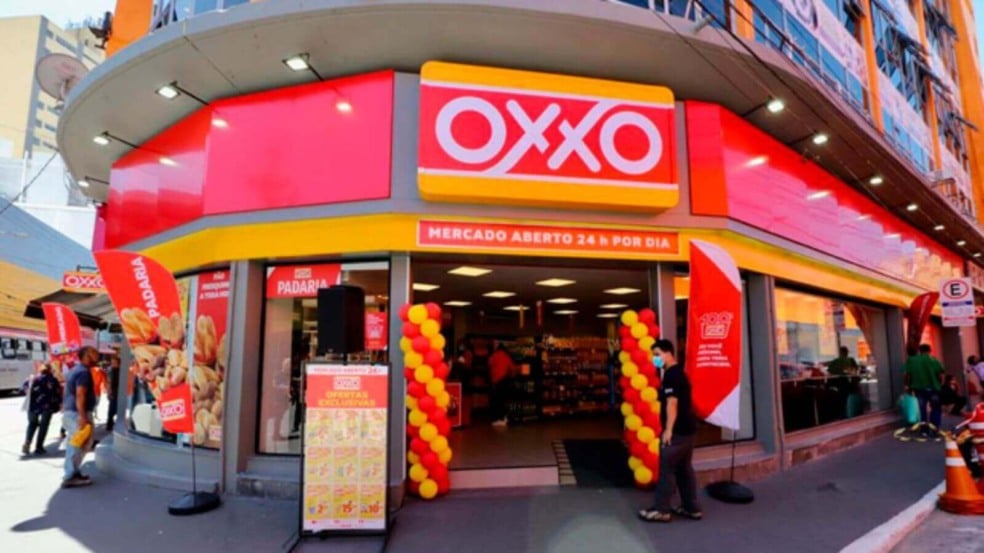 Fachada da loja OXXO em Jundiaí com letreiro vermelho e amarelo, entrada decorada e pessoas passando em frente.