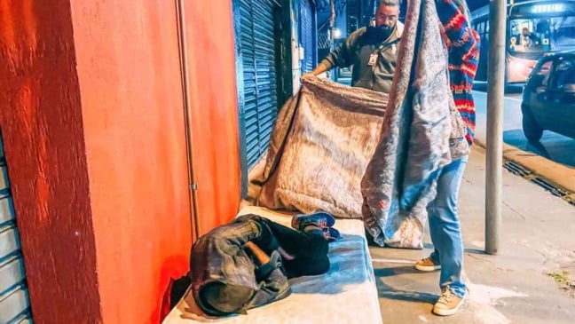 Homem cobrindo pessoa em situação de rua em Jundiaí