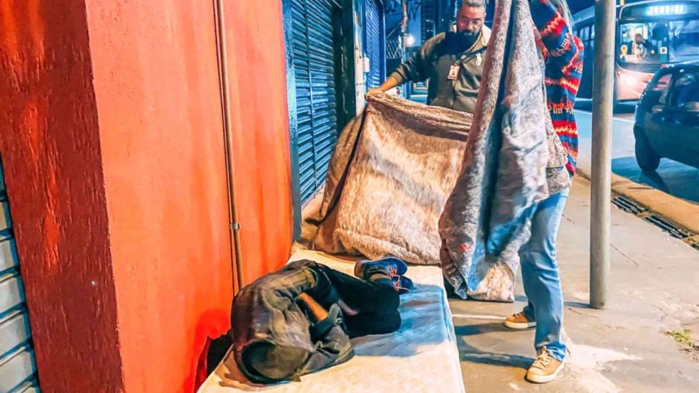 Homem cobrindo pessoa em situação de rua em Jundiaí