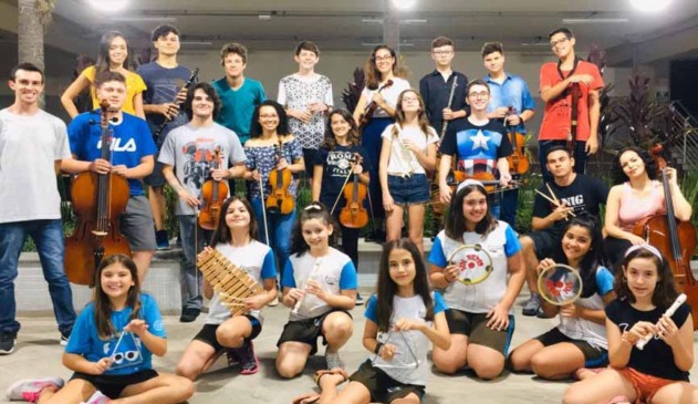Membros de corais, incluindo adultos, idosos e crianças,posam para foto com seus instrumentos musicais