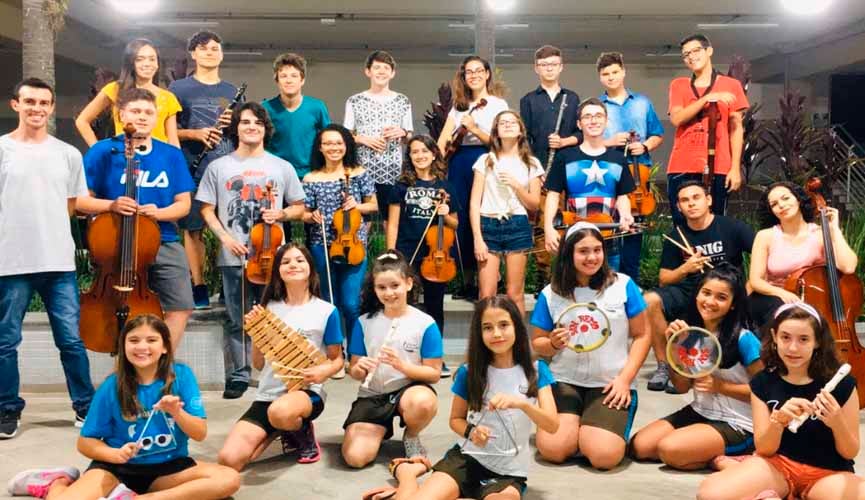 Membros de corais, incluindo adultos, idosos e crianças,posam para foto com seus instrumentos musicais