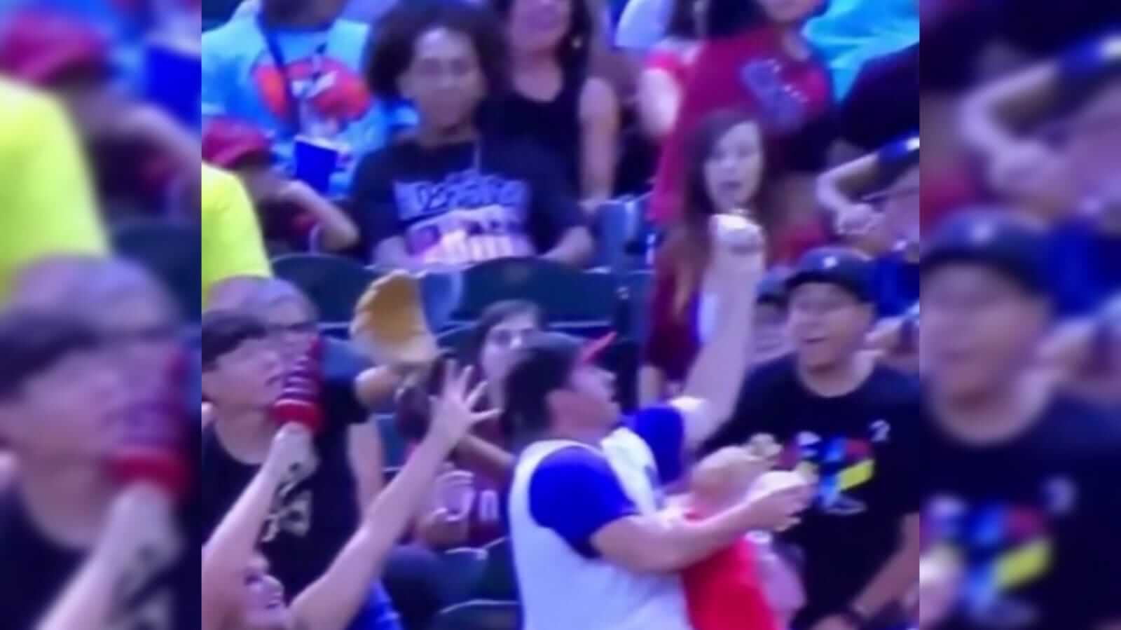 Pai com um bebê no colo e cerveja, consegue pegar a bola de beisebol com a outra mão