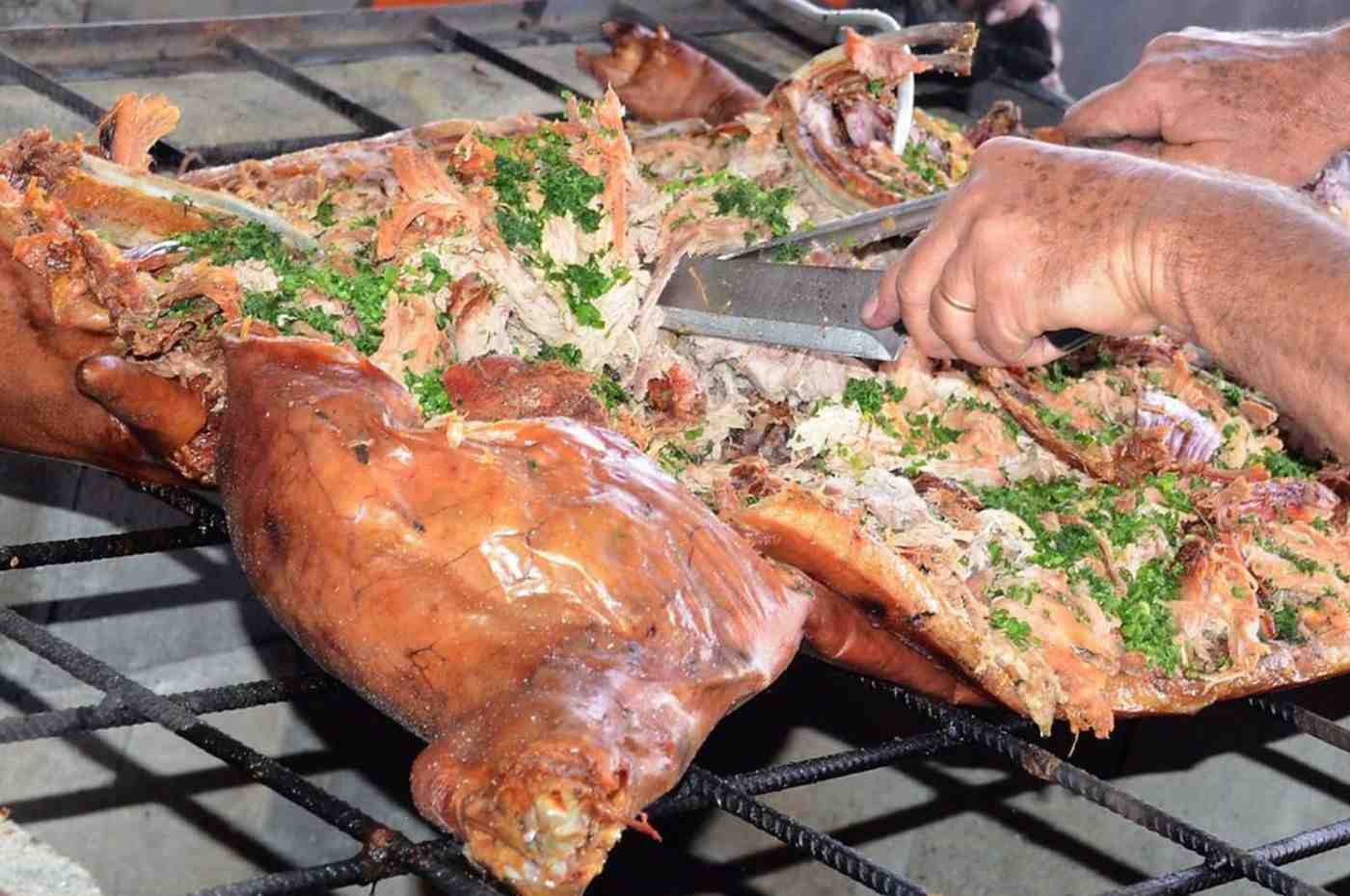 Preparação do tradicional Porco à Paraguaia com carne desfiada e temperos, durante evento beneficente em Jundiaí.