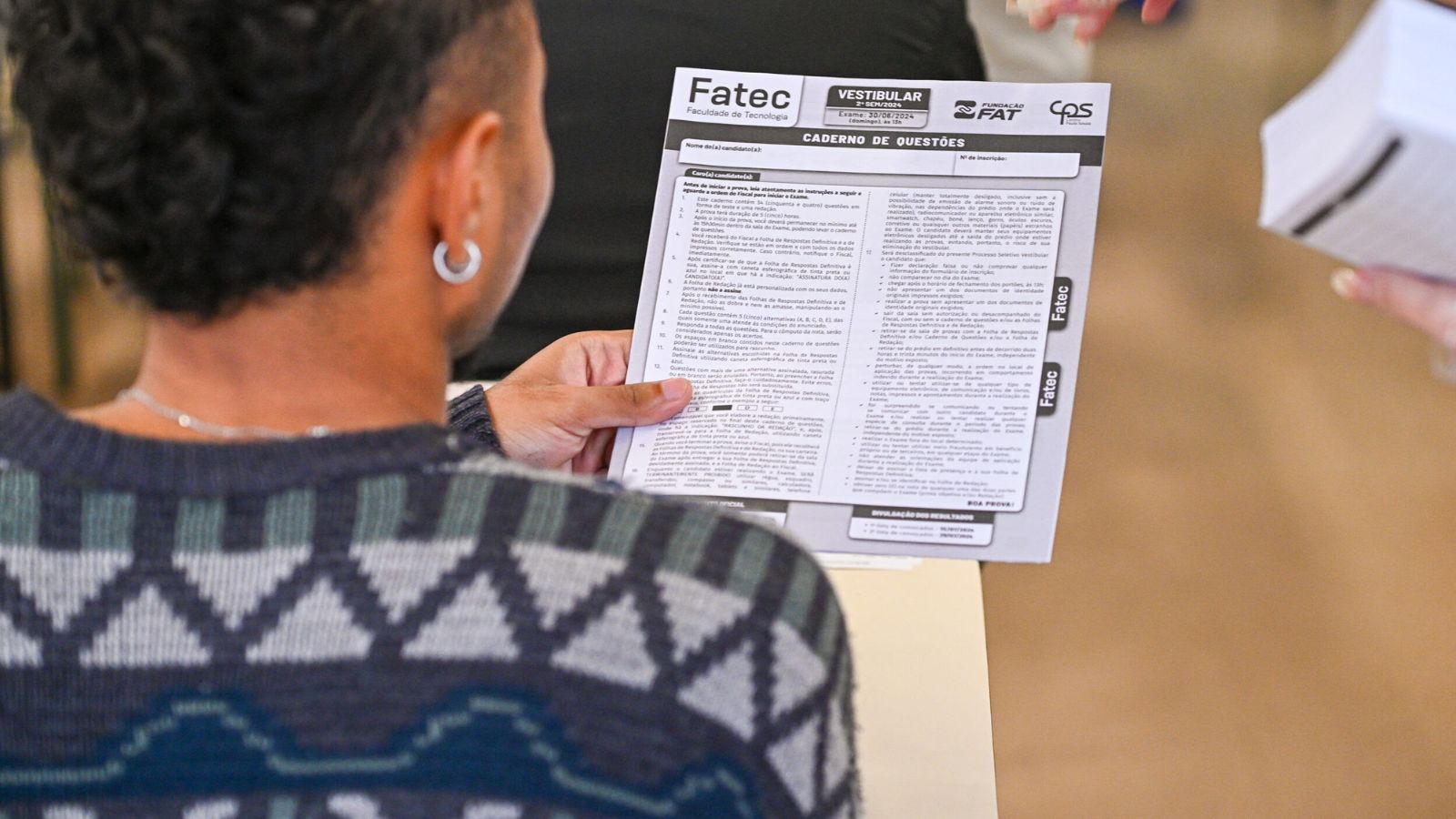 Pessoa com o Vestibular das Fatecs em mãos