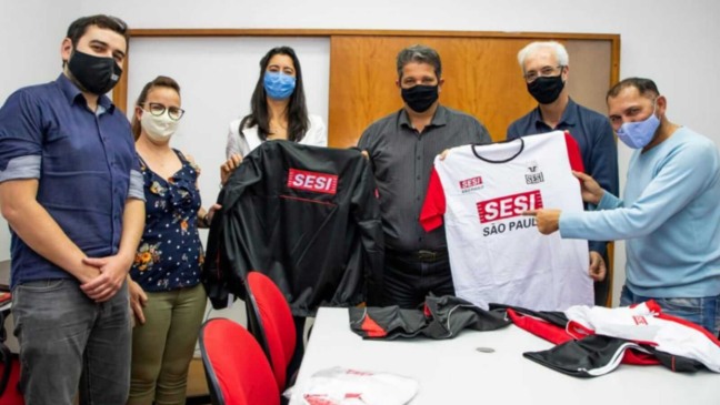 Representantes de Itupeva e do Sesi, segurando uniformes da instituição