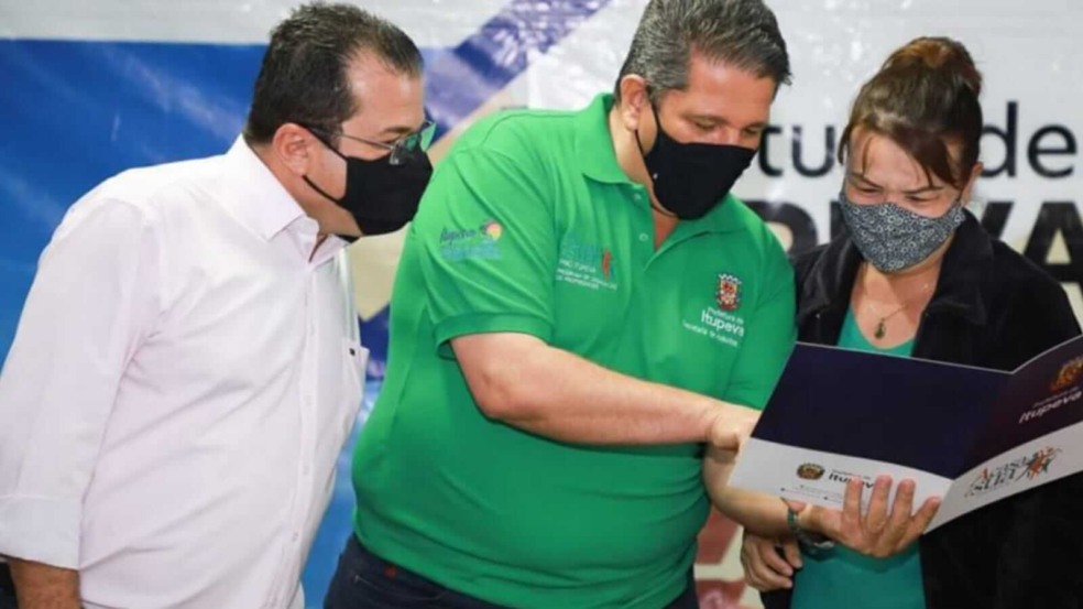 Prefeito e vice-prefeito de Itupeva mostram documento para moradora