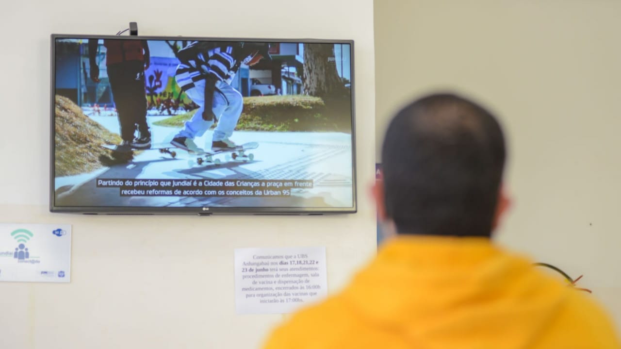 Homem sentado em frente à TV em UBS de Jundiaí