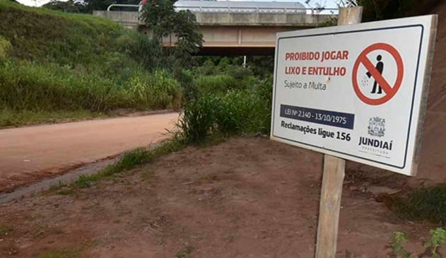 placa em terreno baldio com os dizeres "proibido jogar lixo e entulho, sujeito a multa"