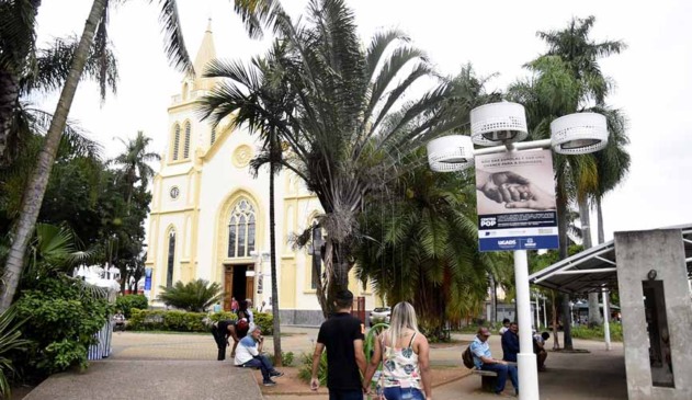 cartaz em poste de praça está escrito "não dar esmolas é dar uma chance para a dignidade", em campanha da prefeitura de jundiaí para que moradores de rua procurem centro de assistência no lugar de receberam esmolas das pessoas. a placa está na praça da catedral e na foto a igreja é observada ao fundo