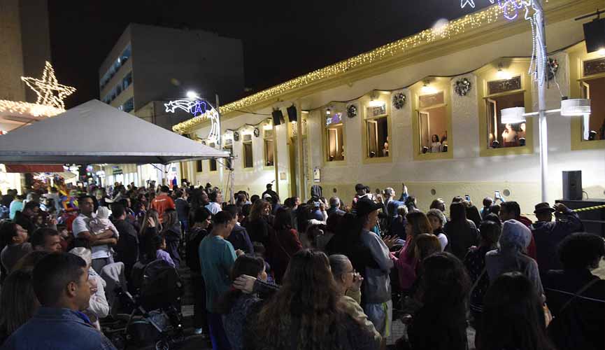 pessoas acompanham coral em janelas de construção em estilo colonial