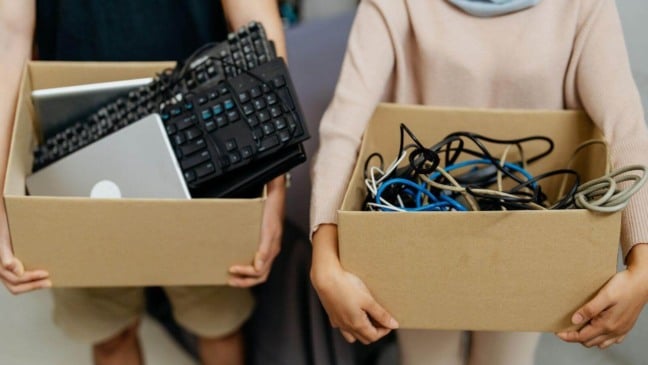Duas pessoas segurando caixas de papelão com lixo eletrônico