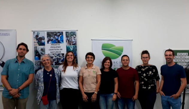 pessoas encostadas em parede lado a lado posam para foto