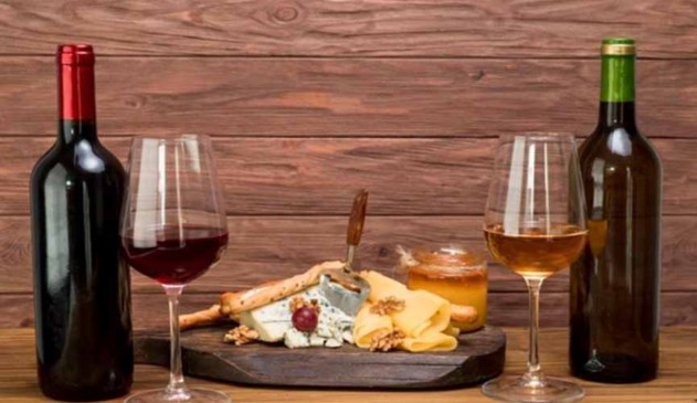 prato com petiscos entre duas taças e garrafas de vinho