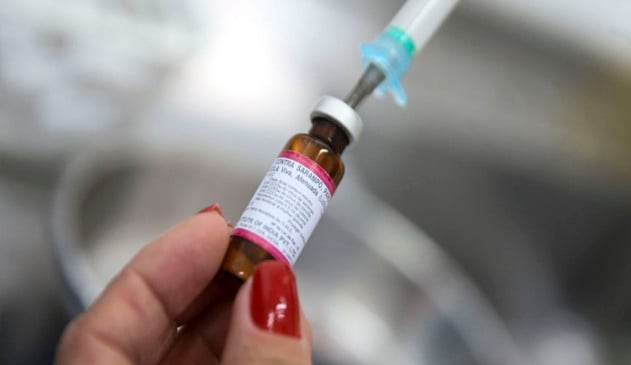 mão de mulher segurando dose de vacina com fundo desfocado