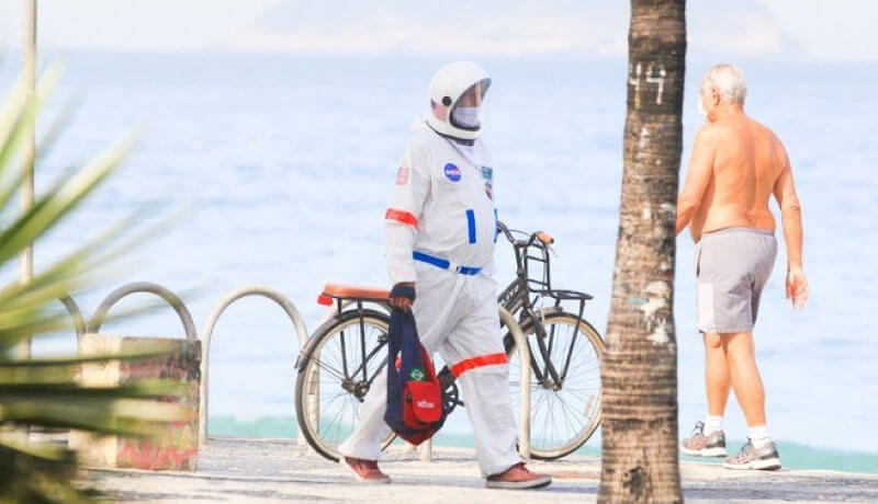Homem passeando pela praia vestido de astronauta