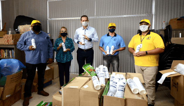 Gestor de saúde e colaboradores de empresa doadora com fracos de álcool nas mãos