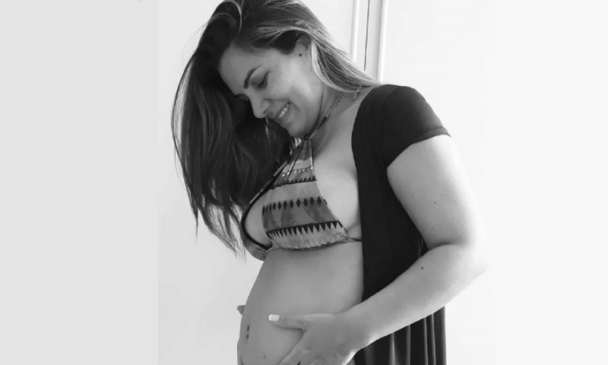 Mulher grávida segura barriga nas mãos