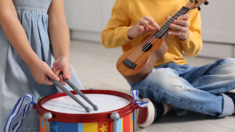 Menina tocando tambor e menino, violão