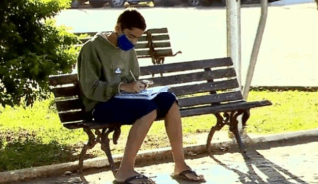 Foto de menino estudando em praça