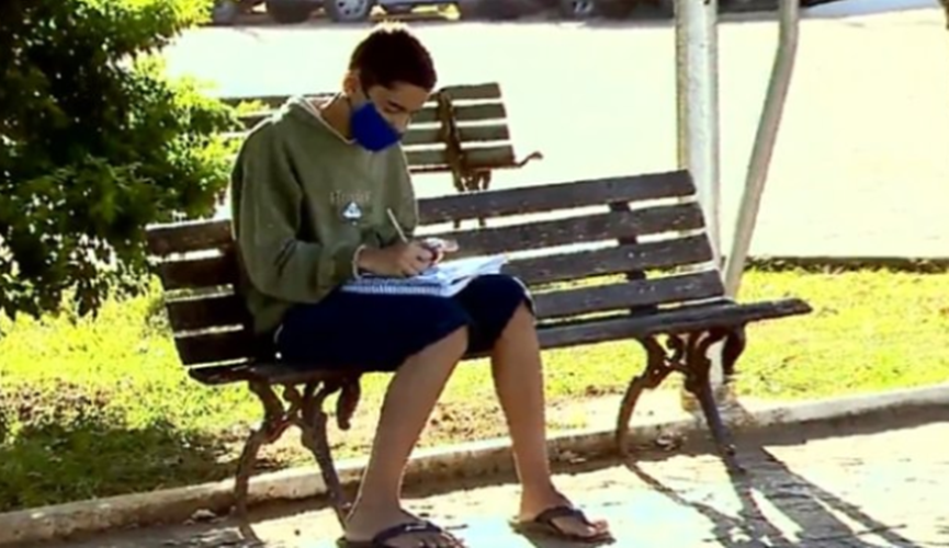 Foto de menino estudando em praça