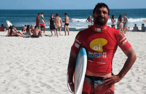 Foto de Leo Neves com prancha na mão ainda na areia