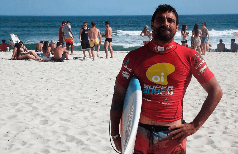 Foto de Leo Neves com prancha na mão ainda na areia