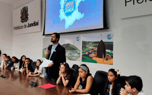 Luiz Fernando Machado fala a frente de mesa com crianças