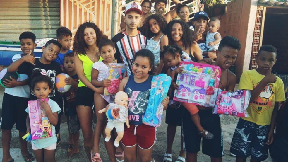 Crianças e jovens com doações em mãos sorriem para foto