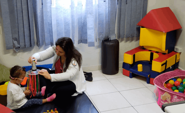 Profissional em sala de recursos auxilia criança com deficiência visual