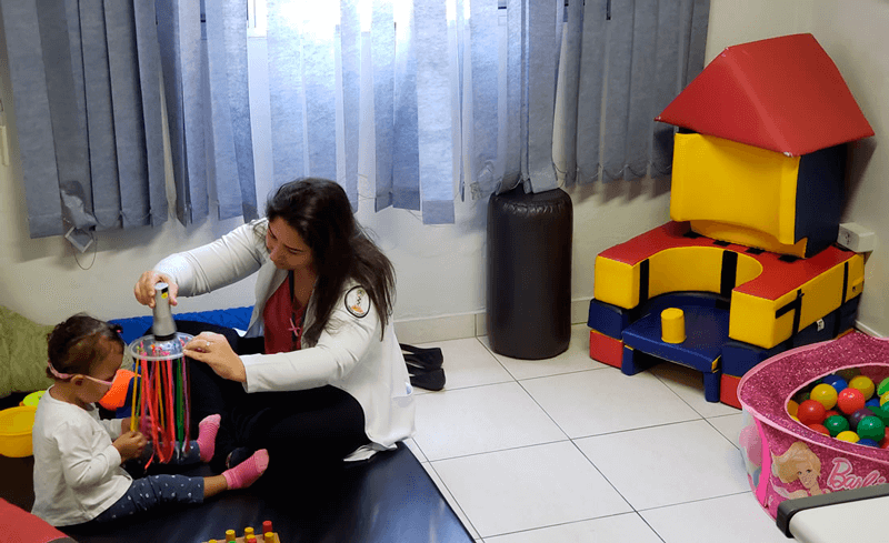 Profissional em sala de recursos auxilia criança com deficiência visual