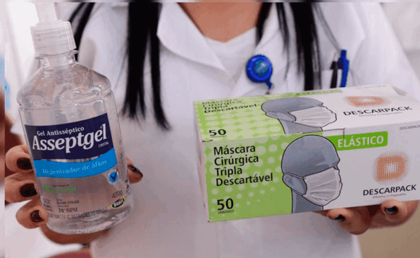 Balconista segura frasco de álcool em gel e caixa de máscaras