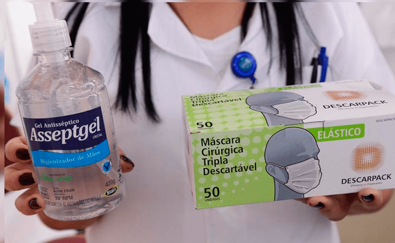 Balconista segura frasco de álcool em gel e caixa de máscaras