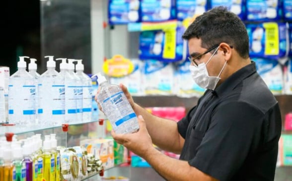 Homem analisa álcool em gel em prateleira