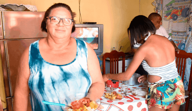 Dona Vera segura prato de comida na sua casa